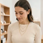 Femme portant des colliers dorés superposés tendance Etam dans une boutique parisienne minimaliste