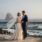 Couple de mariés sur la promenade côtière de Biarritz avec vue sur le Rocher de la Vierge en arrière-plan